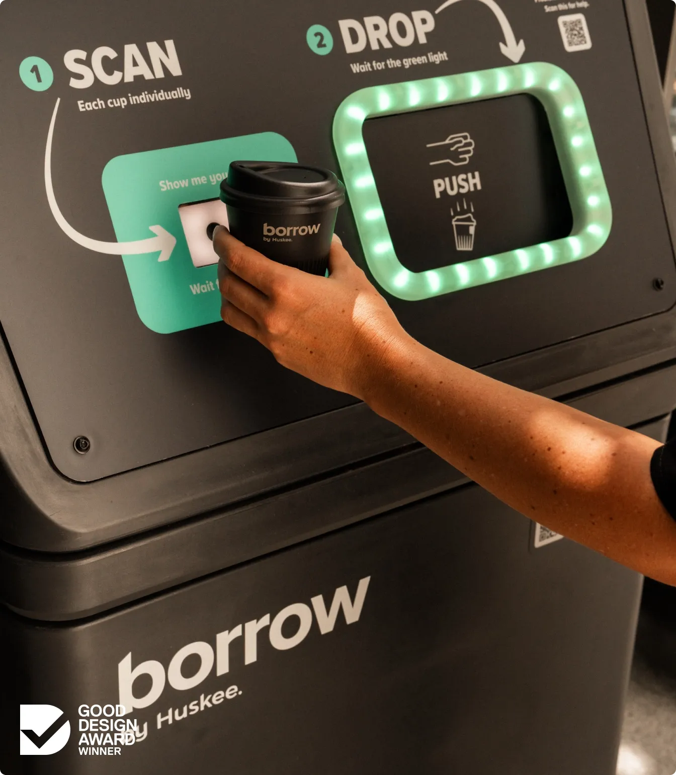 Close up of a Borrow cup held to the scan pad, the drop slot lit green beside it