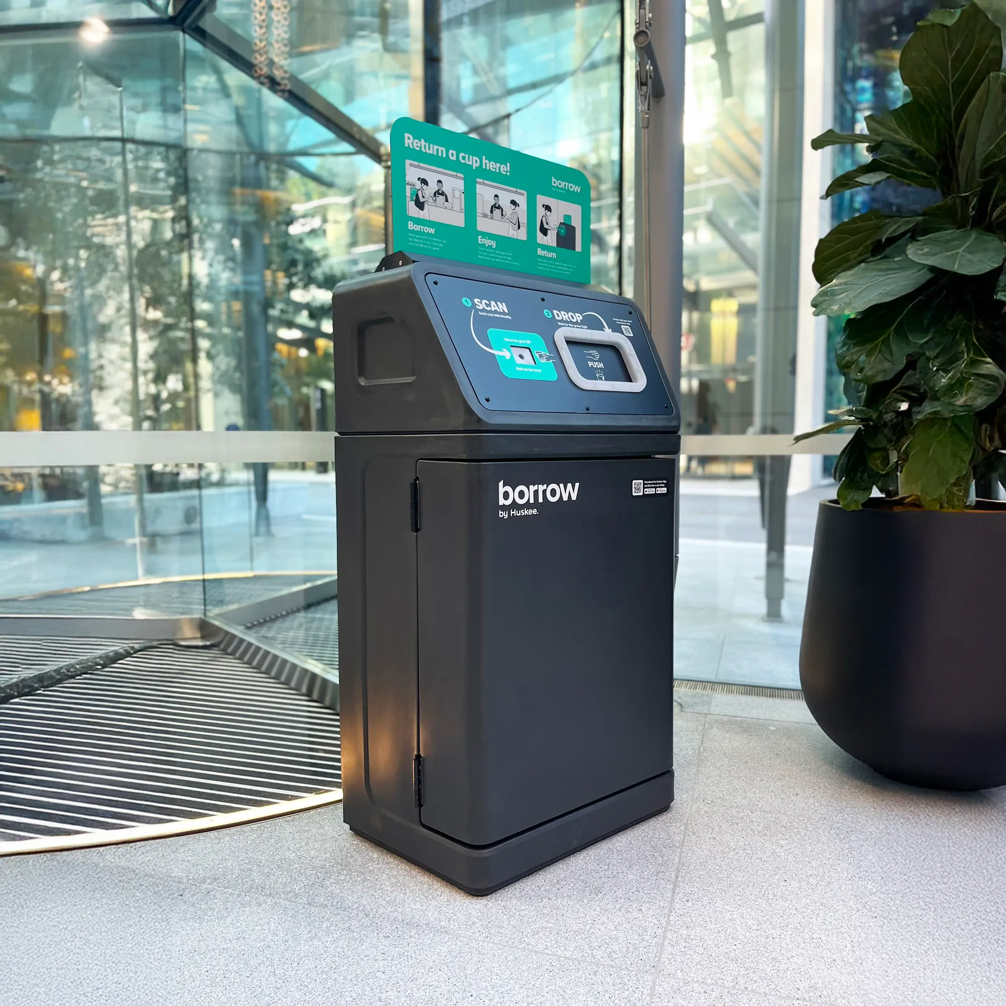 A Borrow reuse kiosk standing in a glass-walled public concourse, its touchscreen showing return instructions