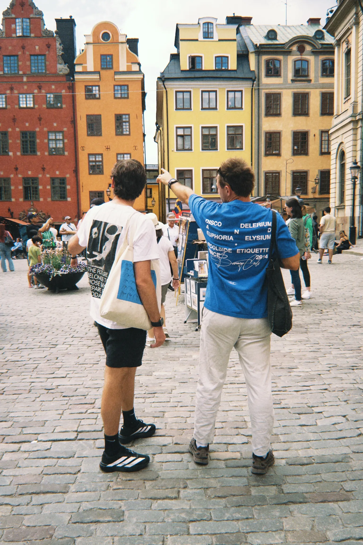 Two people looking up at buildings in a city square