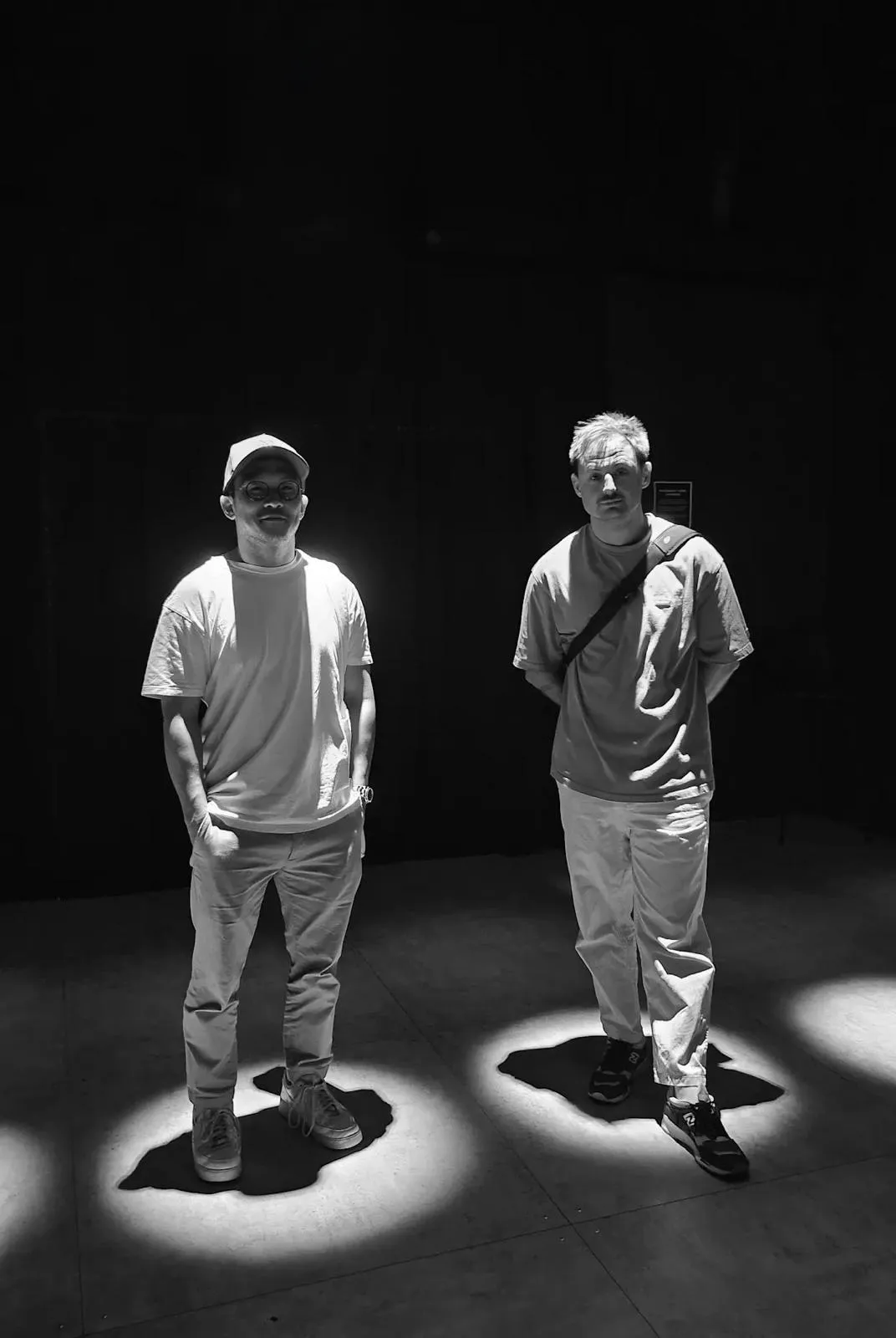Two people lit by spotlights on a dark stage