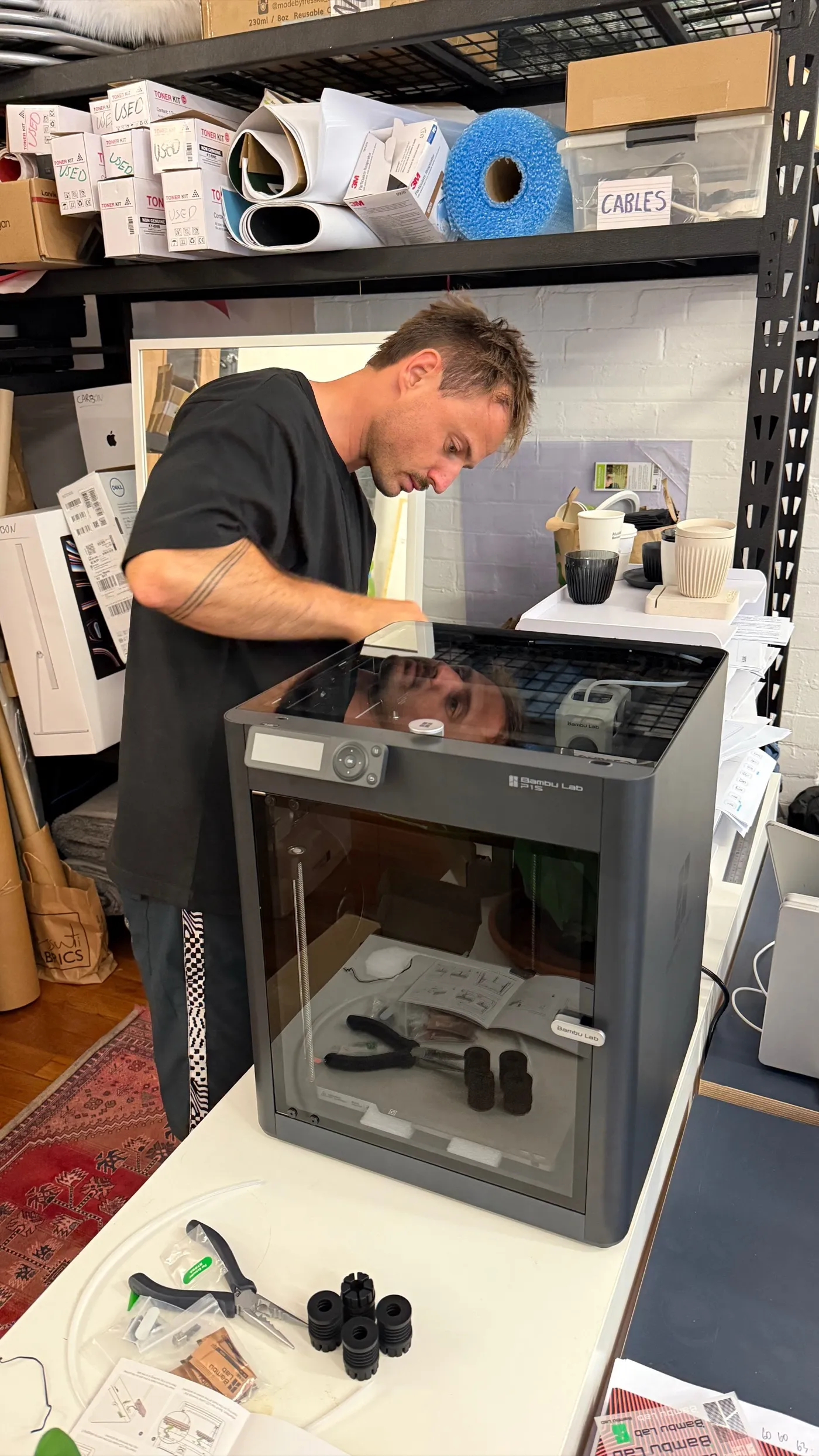 Mike Stevens leaning over a 3D printer in the studio workshop