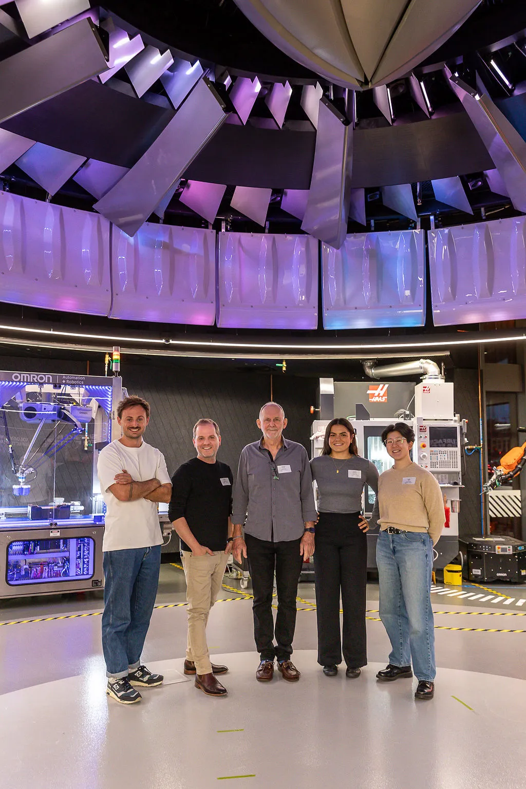 Five people standing together in a robotics workshop